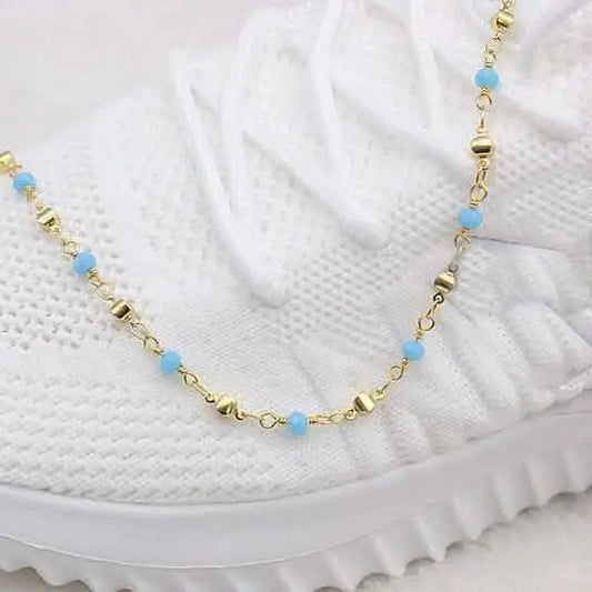Gold-tone ankle bracelet with turquoise round beads on link chain, partial view