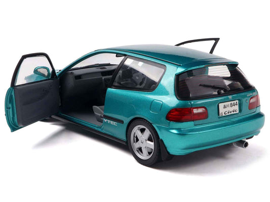 Teal 1/18 diecast coupe model car, rear three-quarter view with open side door.