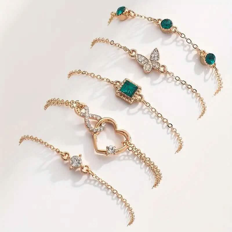 Gold-tone rhinestone bracelet set with butterfly, heart, and green oval stone charms.