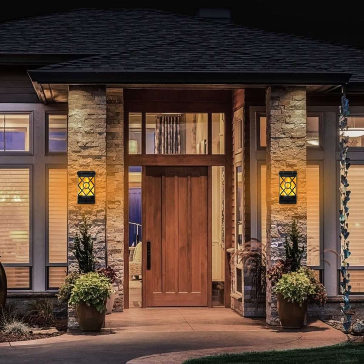 Pair of solar flame lights by front door with warm glow through black lattice