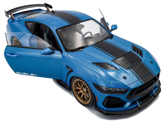 Blue diecast model car with black hood stripes, angled side view, gold wheels