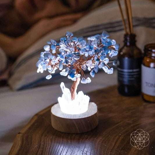 Lit aquamarine blue crystal tree lamp with copper wire branches on wood base