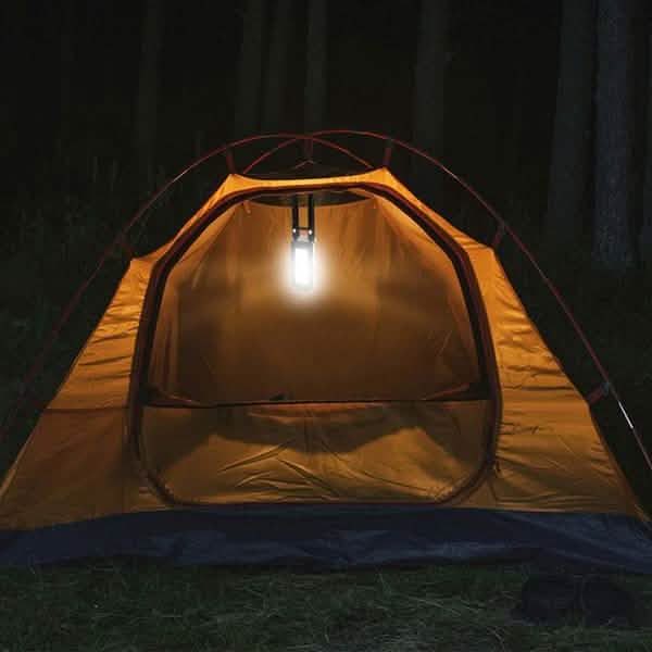 Hanging rechargeable LED outdoor light glowing above a camping tent at night