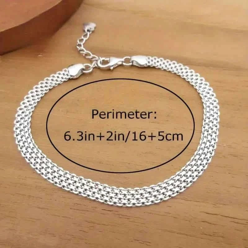 Silver mesh chain bracelet lying flat on a wooden surface