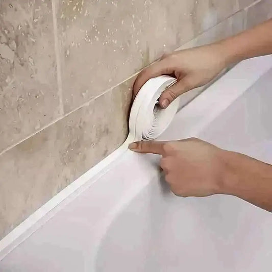 Self-adhesive waterproof caulk strip pressed into tub and tile corner seam, white tape