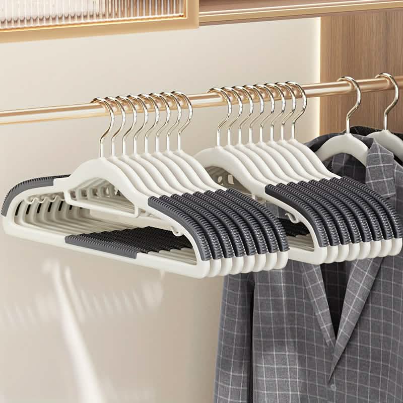 Plastic clothes hangers in white with black grip pads, multiple on metal rod
