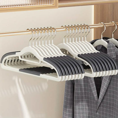 Plastic clothes hangers in white with black grip pads, multiple on metal rod