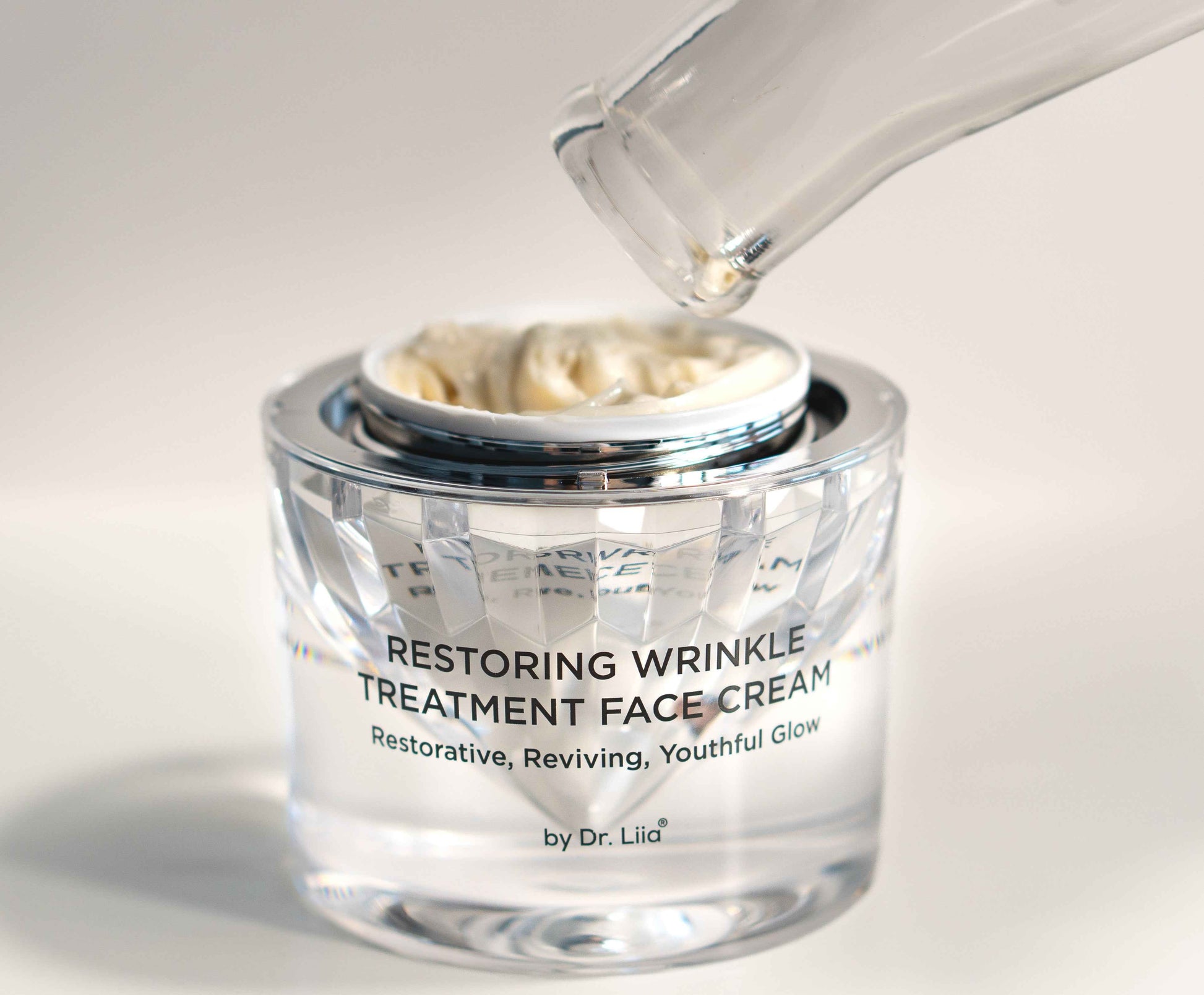 Restoring Wrinkle Treatment face cream jar with applicator dispensing white cream