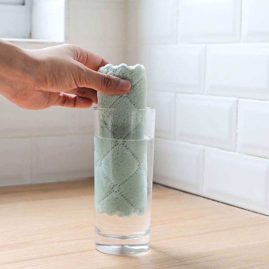 Dish towel roll in a clear glass holder, teal cloth gripped by hand
