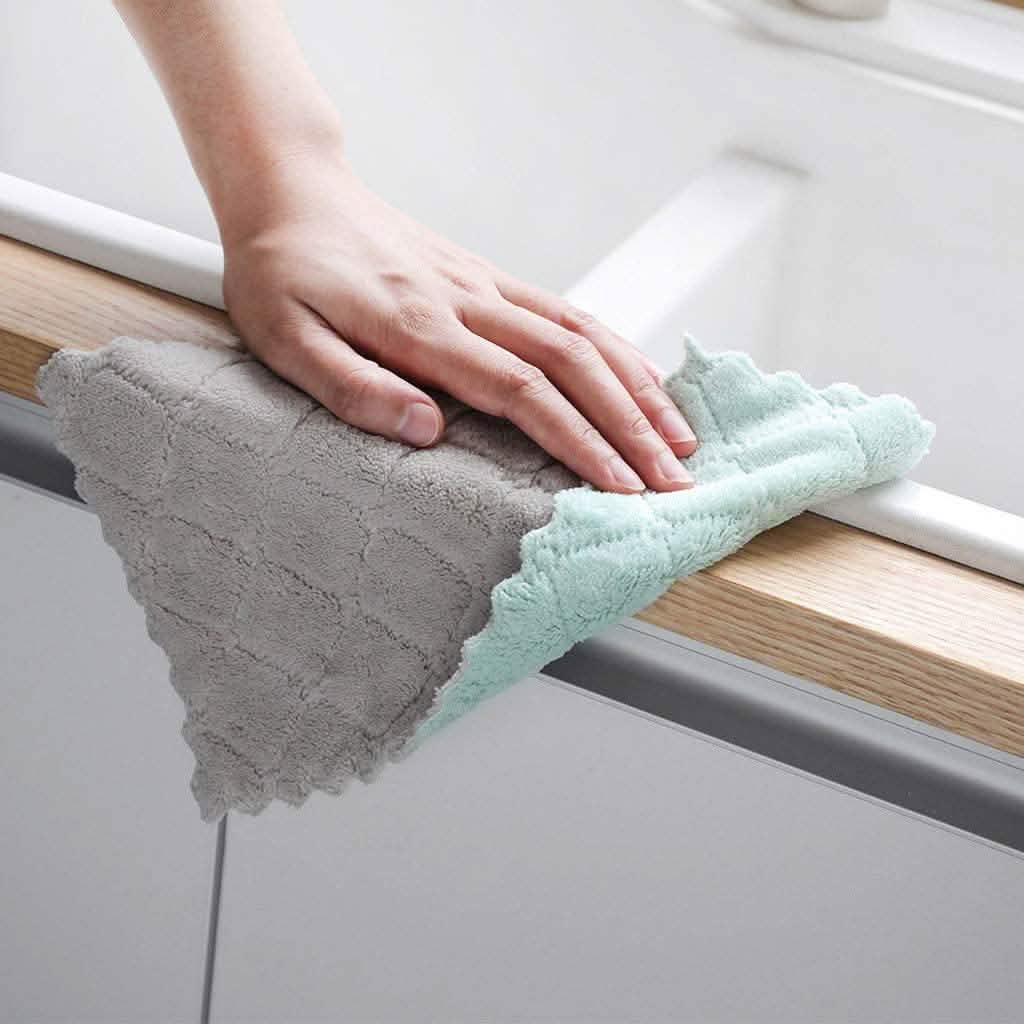 Gray and teal dish towels wiping a countertop edge, textured terry fabric