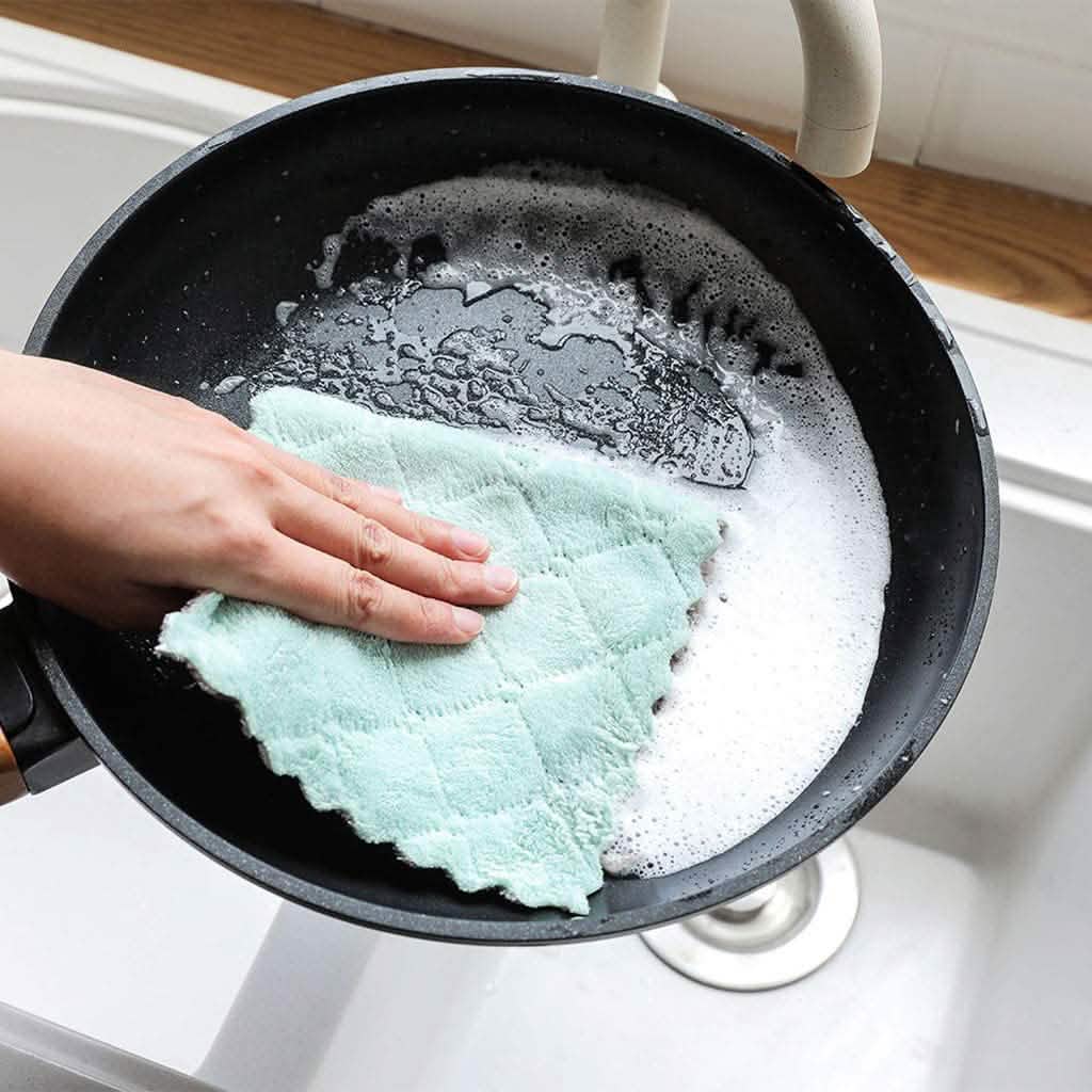 Mint kitchen dish towel wiping a nonstick pan on the stove.