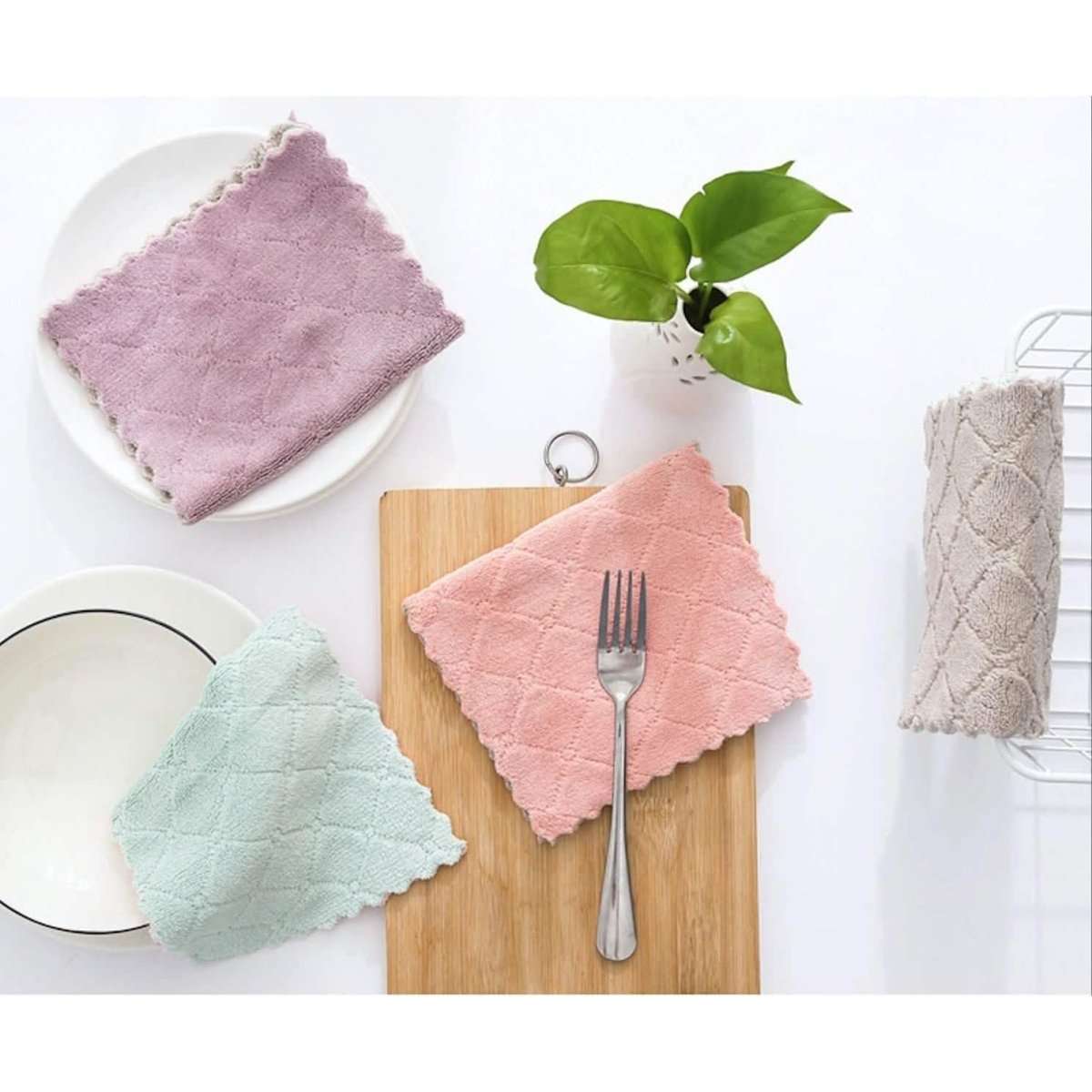 Assorted kitchen dish towels on a plate and cutting board: lavender, pink, mint, beige.
