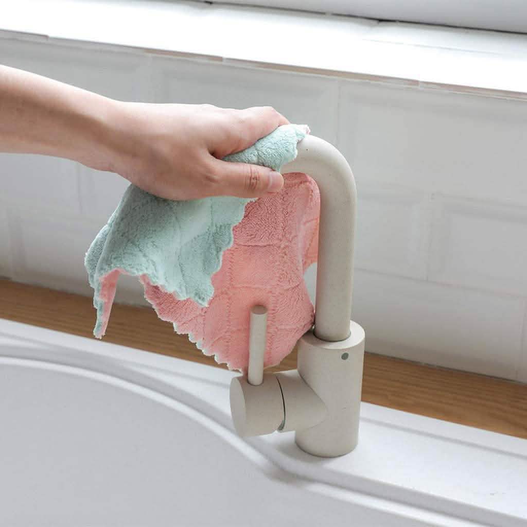 Kitchen dish towels: mint green and pink on a sink ledge near a faucet