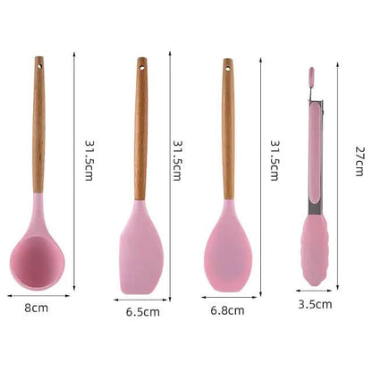 Pink silicone kitchen tools with wood handles, including ladle, spatula, and whisk