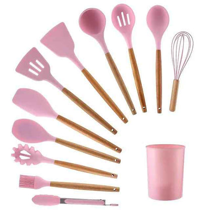 Pink silicone kitchen utensil set with wood handles, including spatulas and whisk