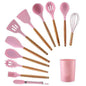 Pink silicone kitchen utensil set with wood handles, including spatulas and whisk