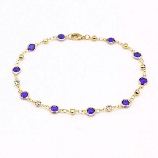 Gold-tone ankle bracelet with blue crystal links on a fine chain
