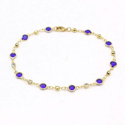 Gold-tone ankle bracelet with blue crystal links on a fine chain