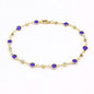 Gold-tone ankle bracelet with blue crystal links on a fine chain