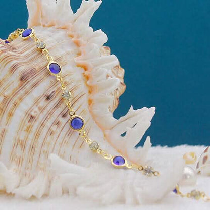 Gold-tone ankle bracelet with blue crystal links and short chain drop
