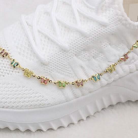 Gold-filled crystal butterfly ankle bracelet on white fabric, multicolor charms
