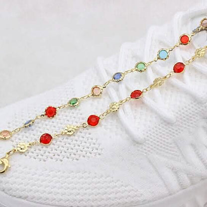 Gold-tone anklet with red crystal links and tiny flower charm stations