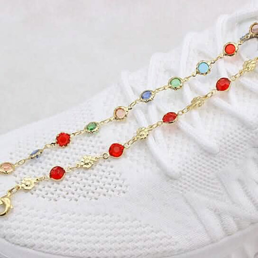 Gold-tone anklet with red crystal links and tiny flower charm stations