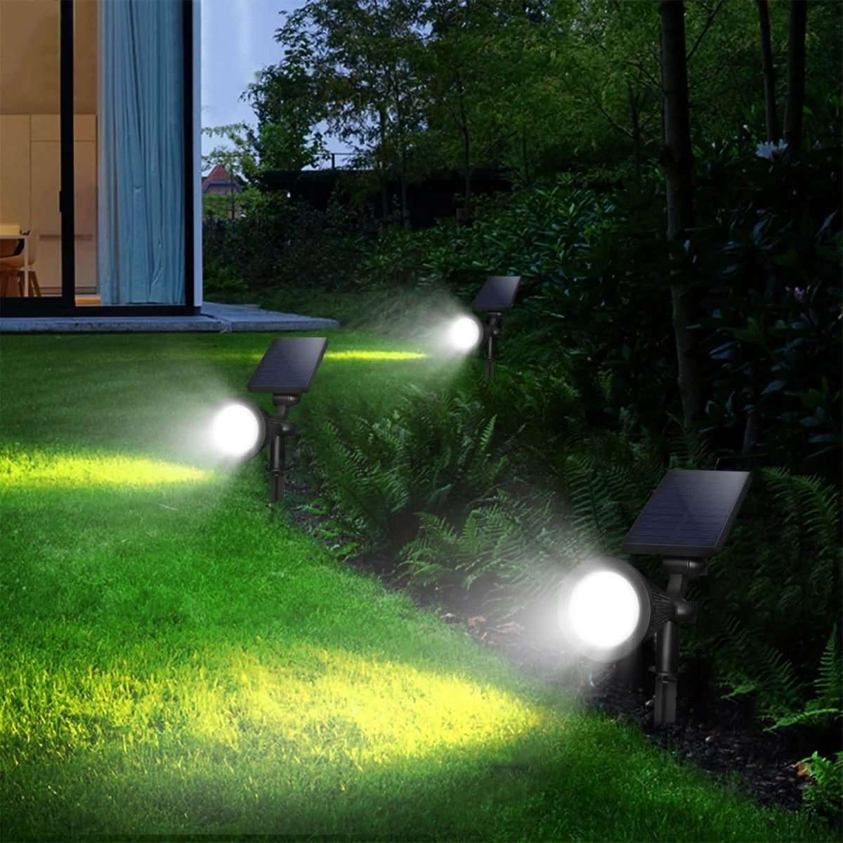 Solar spotlight set with round LED heads and solar panels on outdoor garden stakes