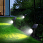 Solar spotlight set with round LED heads and solar panels on outdoor garden stakes
