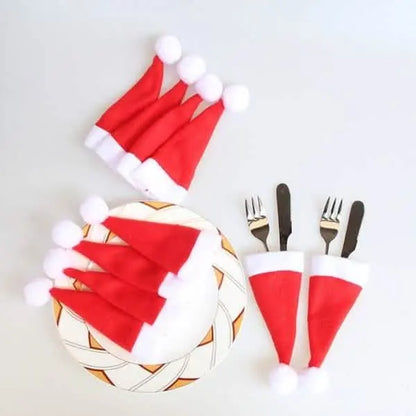 Santa hat utensil holders on a patterned ball with forks and pom-poms
