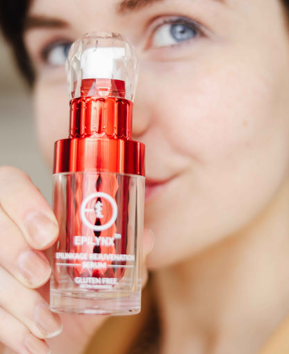 Face serum bottle held in hand with red cap and clear glass body
