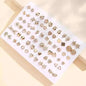 Gold-tone stud earrings set on white card with hearts, stars, flowers, and geometric shapes