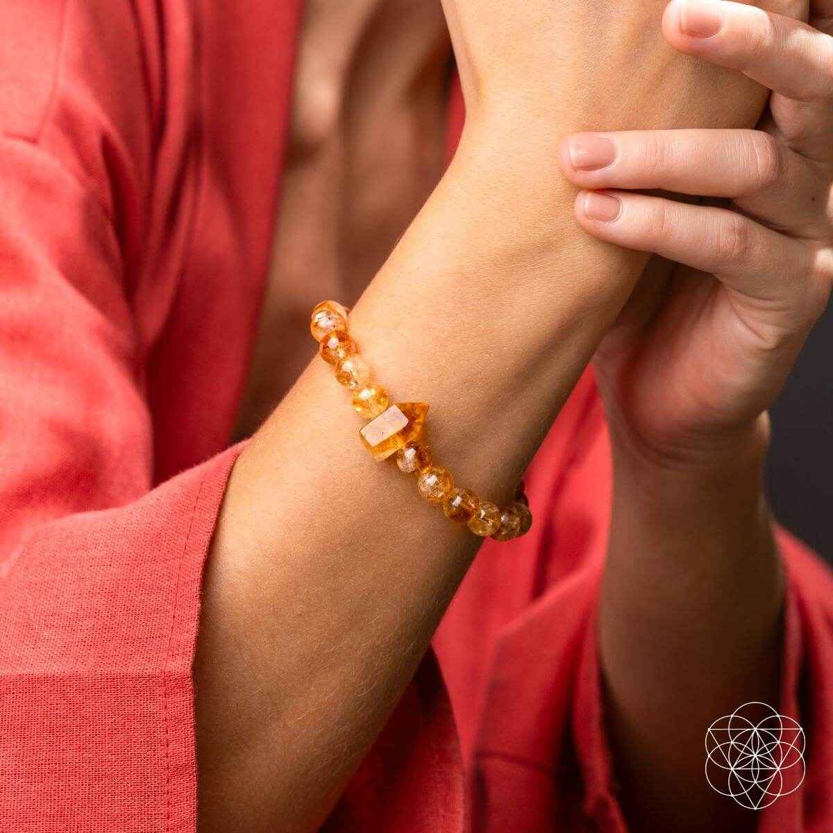 Citrine bracelet on wrist, featuring amber round beads and a pointed crystal centerpiece.