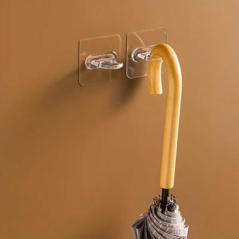 Clear adhesive wall hook holding a yellow-handled tool with black fastener base