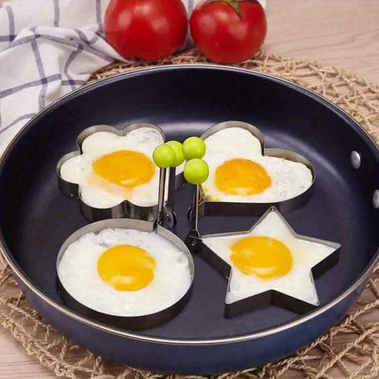 Egg ring mold set with metal rings and handles, shaping four sunny-side eggs