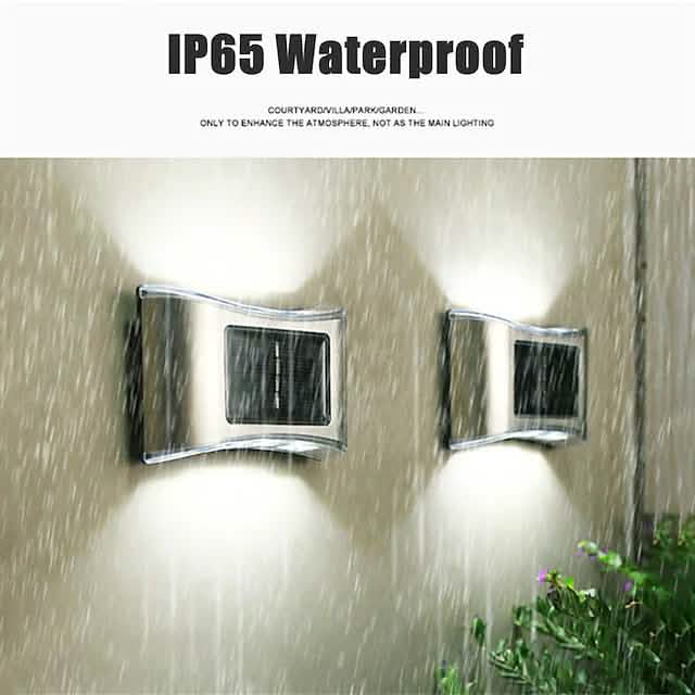Two solar wall LED lights with chrome housings and dark panel windows in rainy conditions