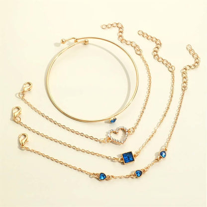 Gold-tone bracelet set with blue square and heart rhinestone charms on multiple chains.