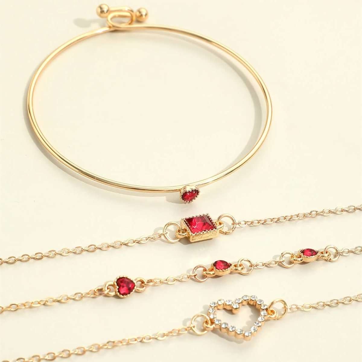 Gold-tone bracelet set with red heart and square rhinestone charms on linked chains.