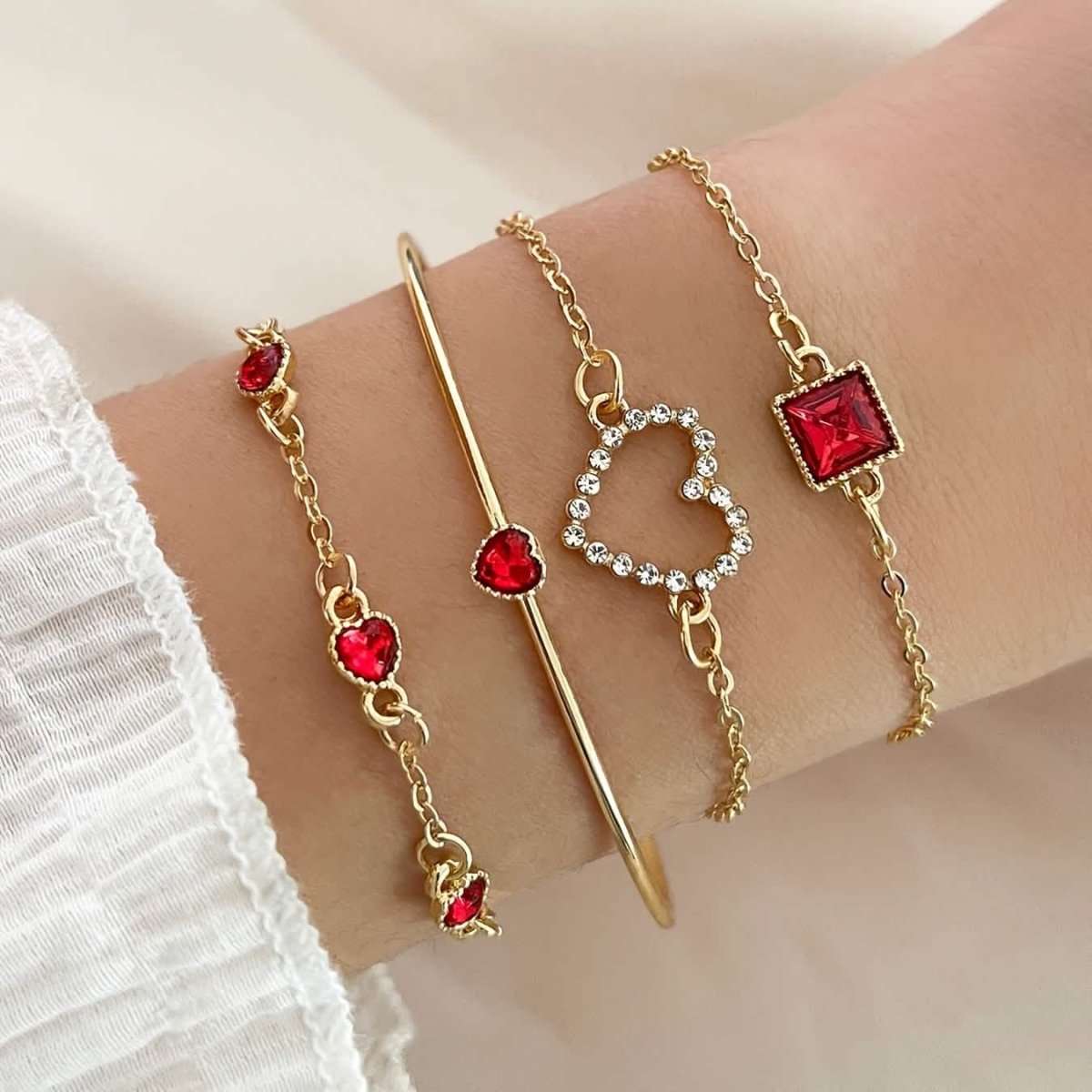 Gold-tone bracelet set with red rhinestone heart, square charm, and chain accents.
