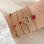 Gold-tone bracelet set with red rhinestone heart, square charm, and chain accents.