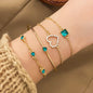 Gold-tone bracelet set with green rhinestone heart and square charms on chain cuffs.