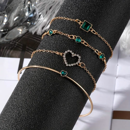 Gold-tone bracelet set with green rhinestone heart and square charms with hinged bangle.