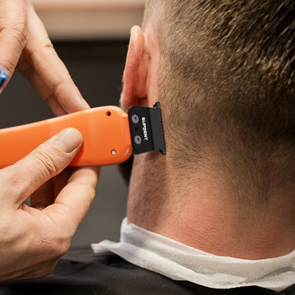 Orange cordless hair trimmer shaving neckline, black blade guard attached