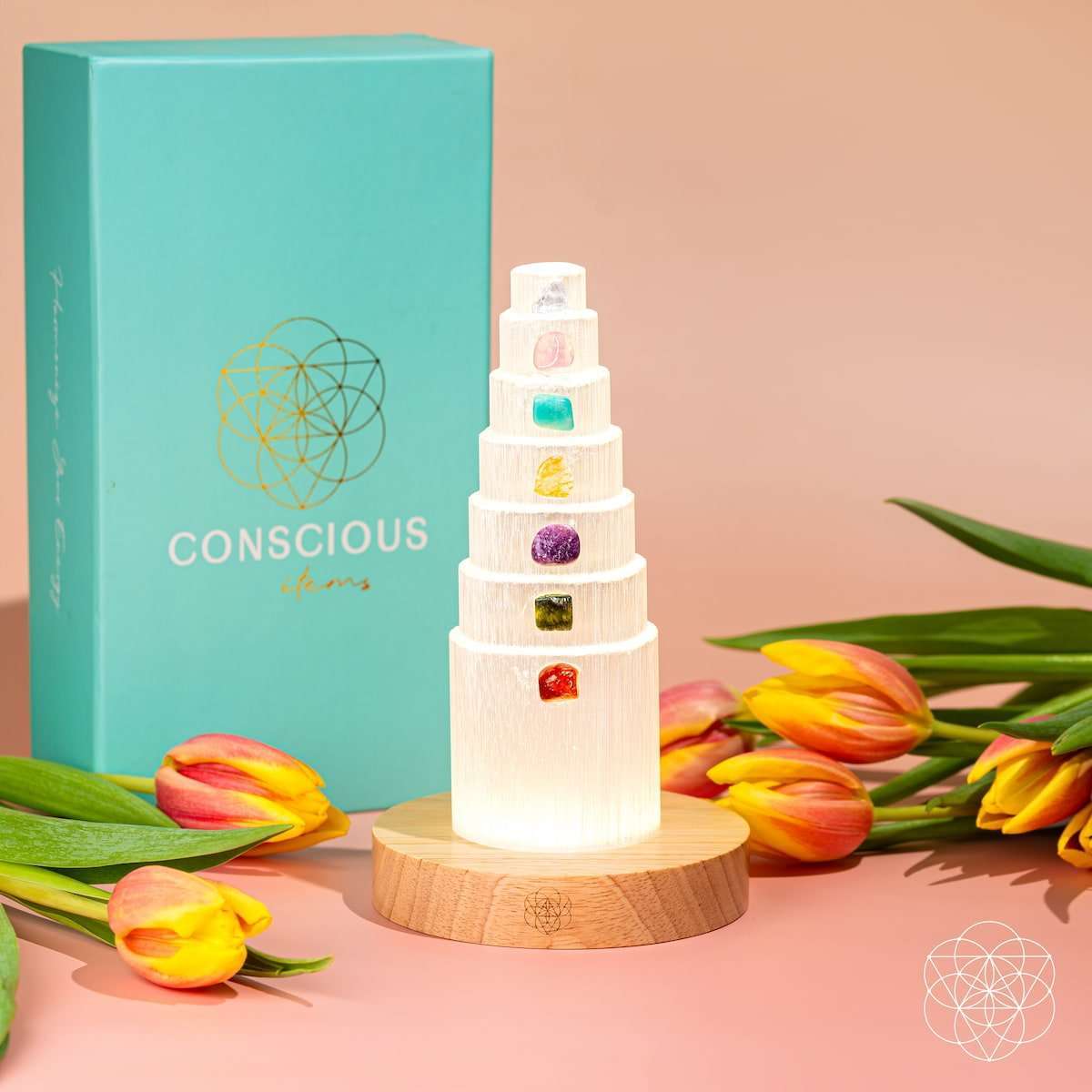 Glowing healing crystal lamp on round wood base beside teal 'conscious' box