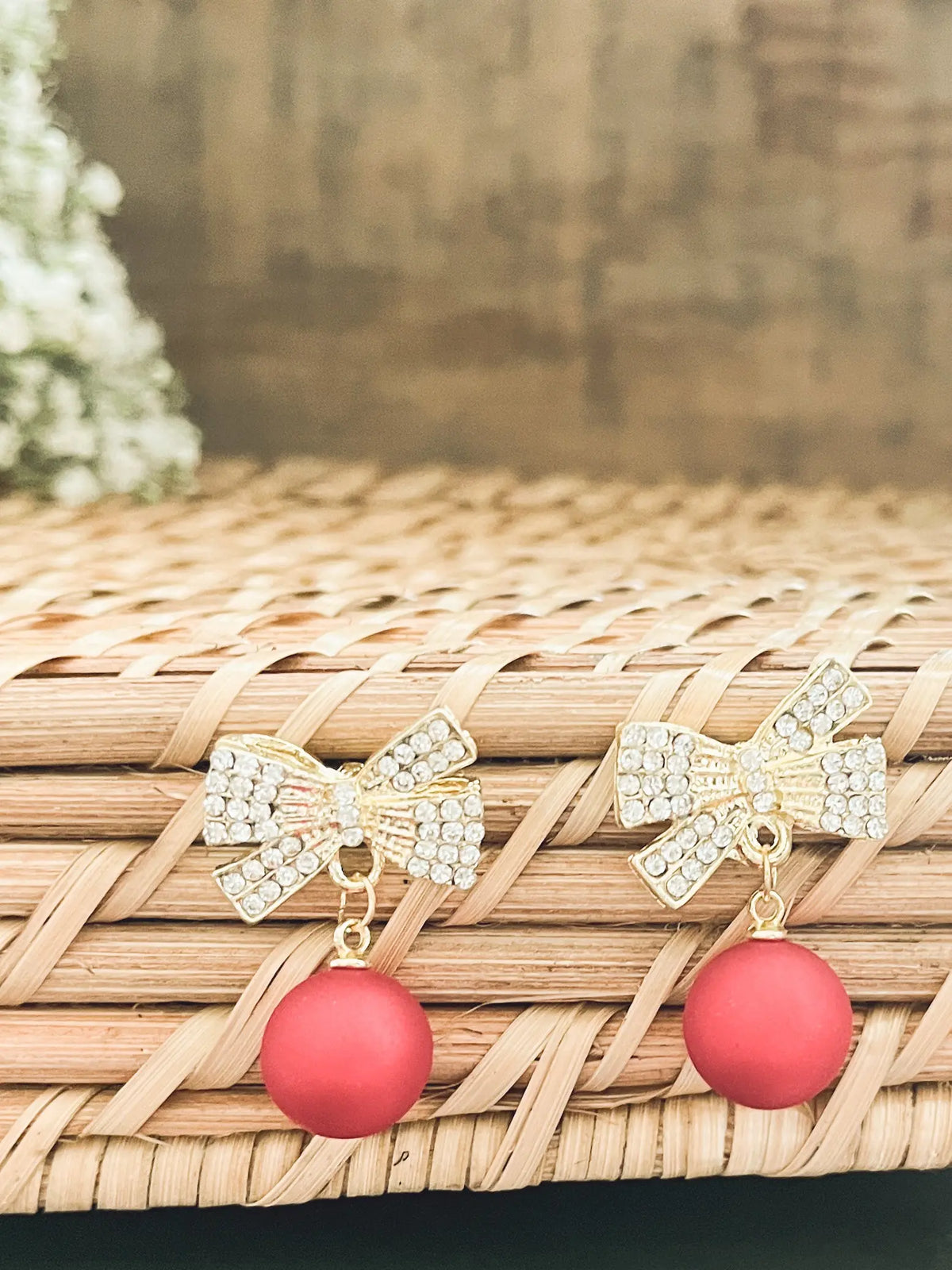 Gold-tone rhinestone bow ornament with red ball drops, angled close-up