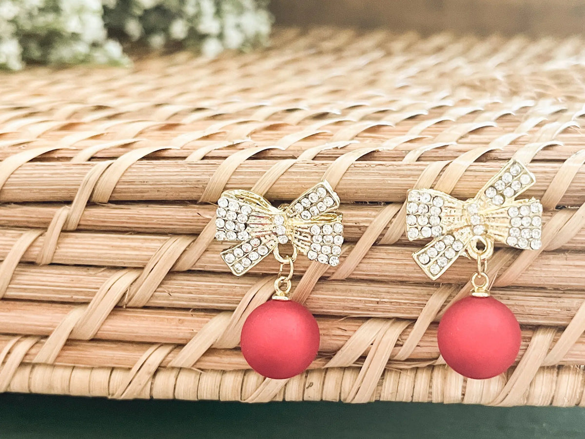 Gold-tone rhinestone bow ornament with red ball drops, front view