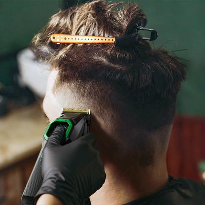 Hair clipper trimming side of head, black-and-green body with gold blade.