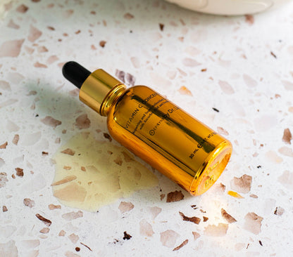 Amber serum bottle with black dropper lying on a speckled countertop