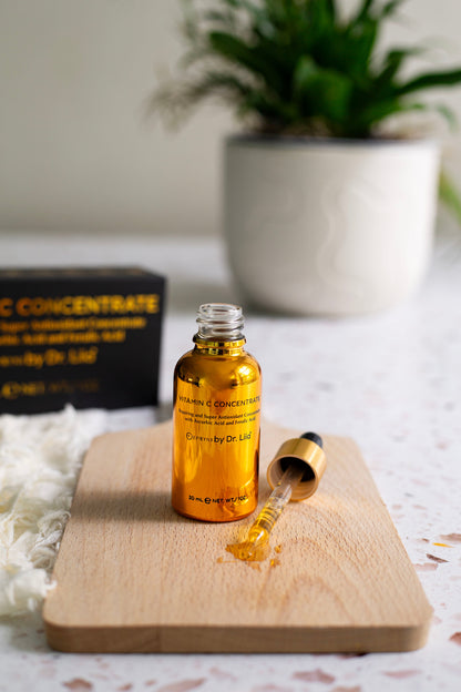 Vitamin C serum bottle with black dropper and small amber droplet on board