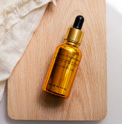 Amber serum bottle with black dropper on wooden tray, gold-toned liquid